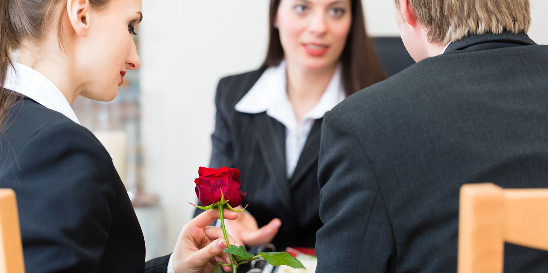 Ein Mann und eine Frau in Businesskleidung sitzen an einem Tisch und führen ein Gespräch.