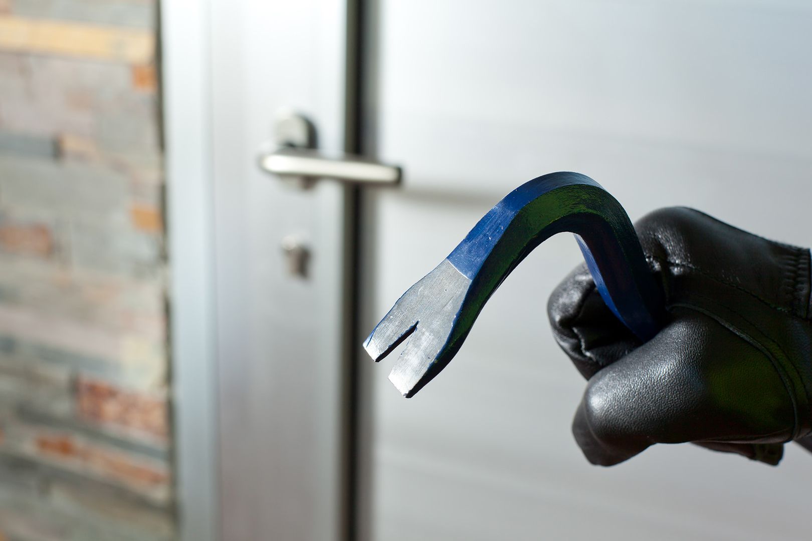 Eine Person mit einem schwarzen Handschuh hält ein blaues Werkzeug in der Hand.