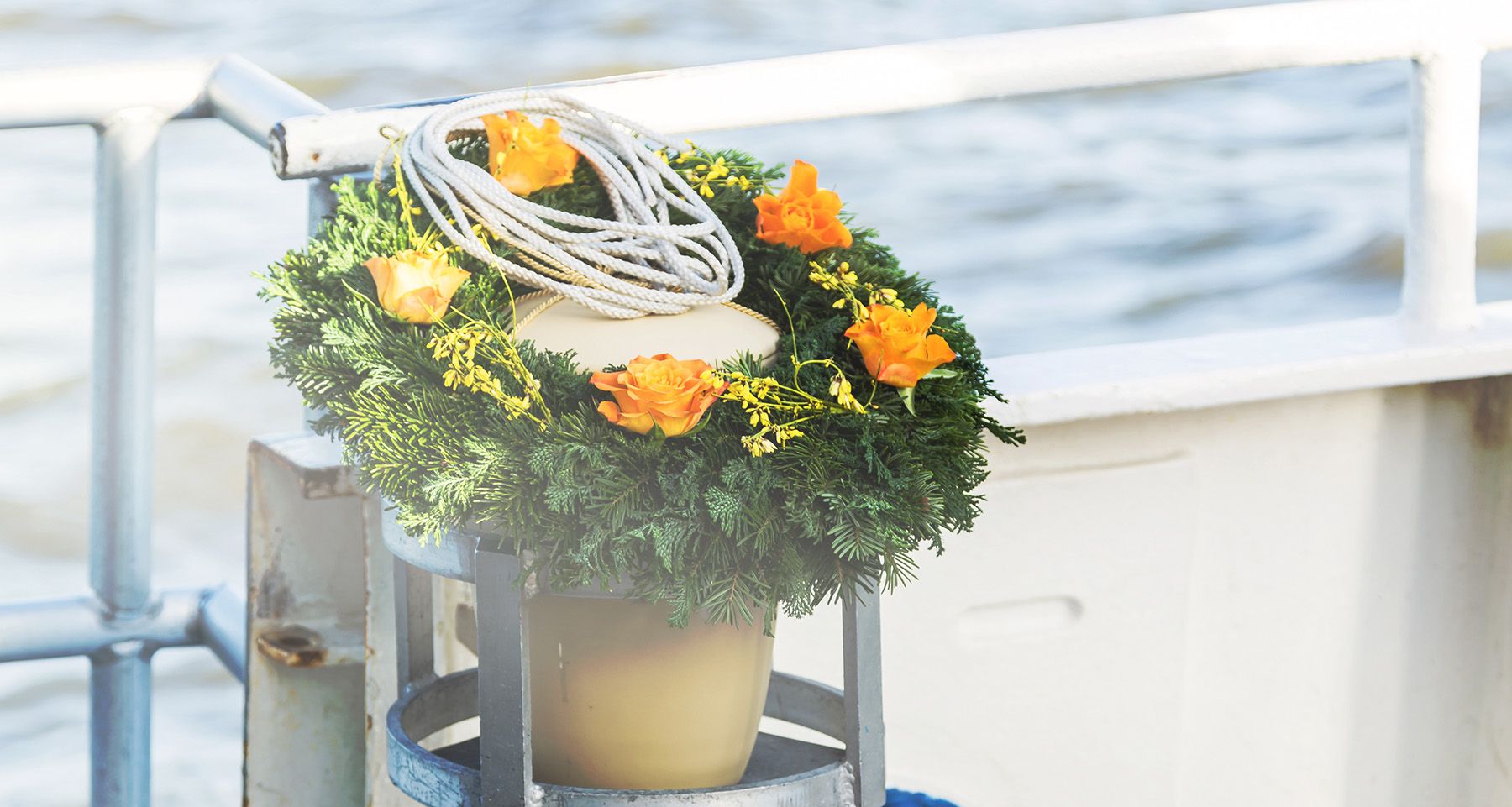 Ein Kranz mit orangefarbenen Blumen auf einem Boot, das sanft auf dem Wasser schwimmt.